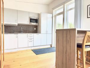 cocina con armarios blancos y mesa de madera en Kostergården en Sydkoster
