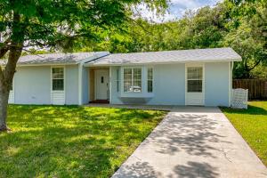 a white house with a tree in a yard at Dog-friendly home with fenced yard, patio, grill, & park across the street in Saint Augustine