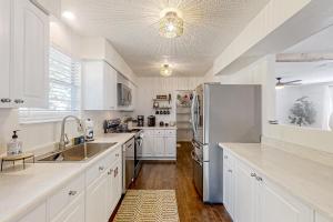 a kitchen with white cabinets and a stainless steel refrigerator at Dog-friendly home with fenced yard, patio, grill, & park across the street in Saint Augustine