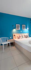 a bedroom with a blue wall and a bed and a chair at ILIDA apartments in Nea Peramos