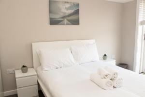 a bedroom with a white bed with towels on it at Cosy 3Bed Bungalow in West Kirby, Free Parking in Frankby