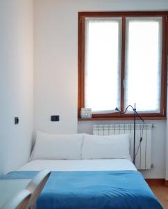 1 dormitorio con 1 cama con sábanas azules y 2 ventanas en Lake View Gateway - by MyHomeInComo en Argegno