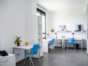 uma cozinha com balcões brancos e cadeiras azuis em Apartamentos Turísticos UNEATLANTICO em Santander