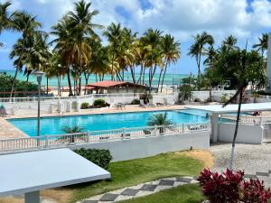 a view of the pool and beach from the balcony of a resort at Beachfront Tropical Tantra Apartment in San Juan