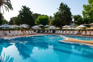 ein großer Pool mit Stühlen und Sonnenschirmen in der Unterkunft Valentin Reina Paguera - Adults Only in Paguera