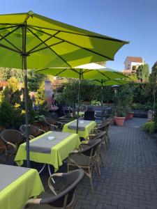 une rangée de tables et de chaises avec des parasols verts dans l'établissement Urberacher Hof, à Rödermark