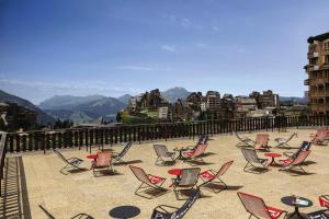 Belambra Clubs Avoriaz - Les Cimes du Soleil في أفورياز: مجموعة من الكراسي والطاولات على فناء مع الجبال