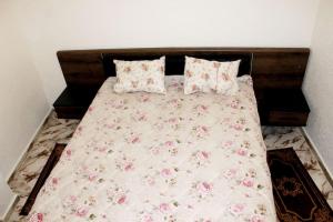 Una cama con flores rosas y almohadas. en Tafoukt house ,tamraght, en Aourir