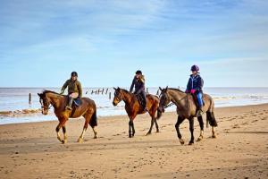 Tres personas montando caballos en la playa en Tafoukt house ,tamraght, en Aourir