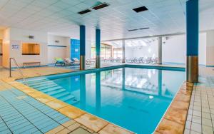a large swimming pool with blue water in a building at Le Nivelet - Duplex aux pieds des pistes toute l'année in La Féclaz