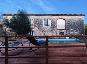 una casa con hamaca en una terraza junto a una piscina en Gîte du Fassac en Saint-Julien-du-Puy