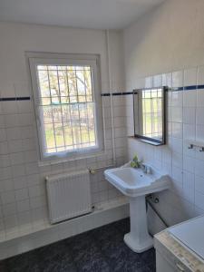 a white bathroom with a sink and a window at FEWO NEUBEEREN in Großbeeren +25 photos