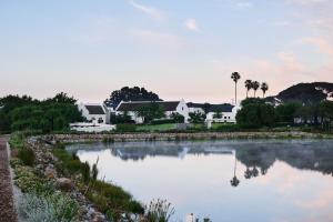 Stellenbosch的住宿－The Hazendal Hotel in the Stellenbosch Winelands by NEWMARK，享有房屋和湖泊的景致。