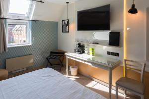 um quarto com uma cama e uma secretária com uma televisão em Cit'Hotel - Hotel Le Cèdre em Noyon