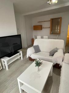 a living room with a white couch and a tv at Precioso Apartamento en Puertollano in Puertollano