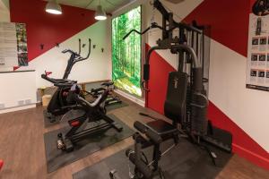 a room with a gym with a treadmill and exercise bike at Cit'Hotel - Hotel Le C&egrave;dre in Noyon