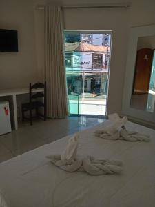 a white bed with towels on it with a window at Hotel Alzira Imperial in São Lourenço