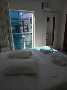 a large white bed in a bedroom with a window at Hotel Alzira Imperial in São Lourenço