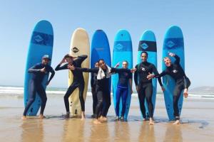 um grupo de pessoas de pé na praia com pranchas de surf em Titrit House awrir em Aourir