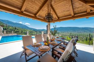a dining room with a table and chairs and a pool at Villa Velaga in Gruda