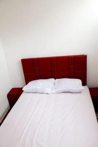 uma cama com uma cabeceira vermelha e duas almofadas brancas em Titrit House awrir em Aourir