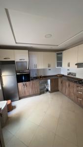 a large kitchen with wooden cabinets and a white tile floor at Appartement de Lux Hay Al MATAR in Nador