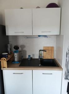 - une cuisine avec des placards blancs et un évier dans l'établissement Appartement T2 très lumineux + PKG, à Toulouse