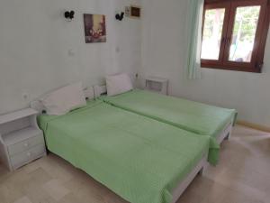 a bedroom with two beds with green sheets and a window at "Patra's" Apartments Patra in Poseidónion