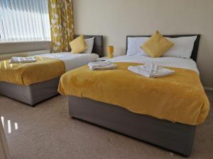 1 dormitorio con 2 camas con sábanas amarillas y ventana en 4 beds with links to motorways, en Leeds