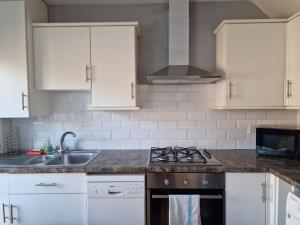 a kitchen with white cabinets and a stove top oven at 4 beds with links to motorways in Leeds