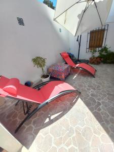 un patio con 2 sillas rojas y una sombrilla en Guesthouse Jazmínes Mozárabes # WIFI, en Baena
