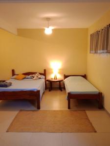 a room with two beds and a table with a lamp at casaOCA in Lençóis