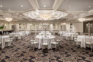 a banquet hall with white tables and chairs and a chandelier at Armon Plaza Montreal Airpt, Trademark Collection by Wyndham in Montréal