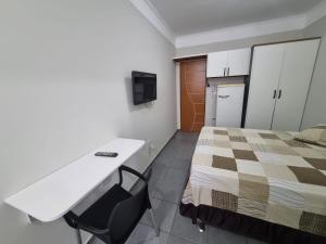 a room with a bed and a desk and a tv at Studio GT in São Carlos