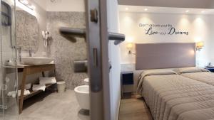 a bedroom with a bed and a bathroom with a sink at Hotel La Serena in Bibione