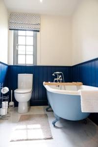 een blauwe badkamer met een bad en een toilet bij Escape Ordinary at Lough Erne Golf Village No.52 in Enniskillen