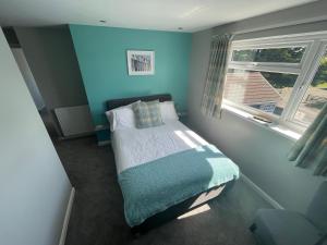 a small bedroom with a bed with a blue wall at Pen Mar Guest House B&B in Tenby