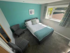 a bedroom with a bed and a chair and a window at Pen Mar Guest House in Tenby