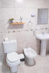 a white bathroom with a toilet and a sink at Apartamentos Matices in El Calafate