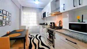 uma cozinha com armários brancos, uma mesa e um balcão em Fully Furnished Stylish Apartment in Antalya em Antalya