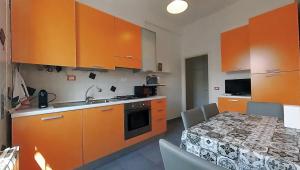 eine Küche mit orangefarbenen Schränken und einem Tisch mit Stühlen in der Unterkunft VIOLA - A Due Passi Dal Mare in Savona