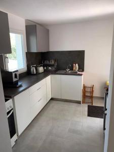 a kitchen with white cabinets and a black counter top at Chata nad kúpaliskom Santovka in Santovka