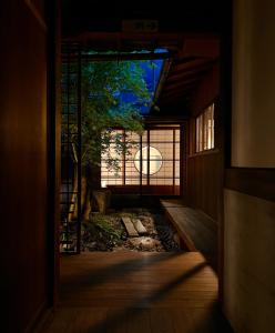 een deur naar een kamer met een boom erin bij 古民家の宿宰嘉庵 TraditionalJapaniseHotel Saikaan in Maizuru