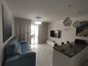 a living room with a blue couch and a kitchen at Apartment Malibu Sun & Relax in Adeje
