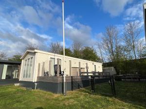 een klein gebouw met een vlaggenmast in een tuin bij Chalet Havenzicht Eernewoude in Earnewâld