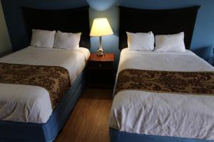 a hotel room with two beds and a lamp at 121 Motel Battleboro in Battleboro