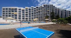 a tennis court in front of a large building at Enjoy the sea and pool in Playa de las Americas in Playa de las Americas