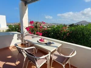 a table and chairs on a balcony with flowers at Paros Reppas House "Livadia" in Parikia