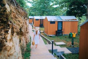 a woman walking down a sidewalk in front of a row of houses at Bobocabin Madasari, Pangandaran in Bulakbenda