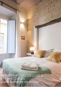 1 dormitorio con 1 cama grande y pared de ladrillo en Boutike Apartments, en Sevilla